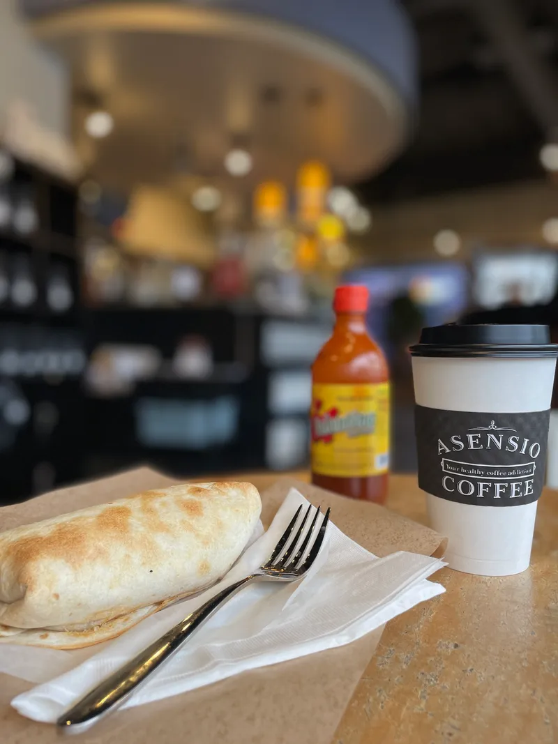 Branded cup held in hand inside Asensio Coffee