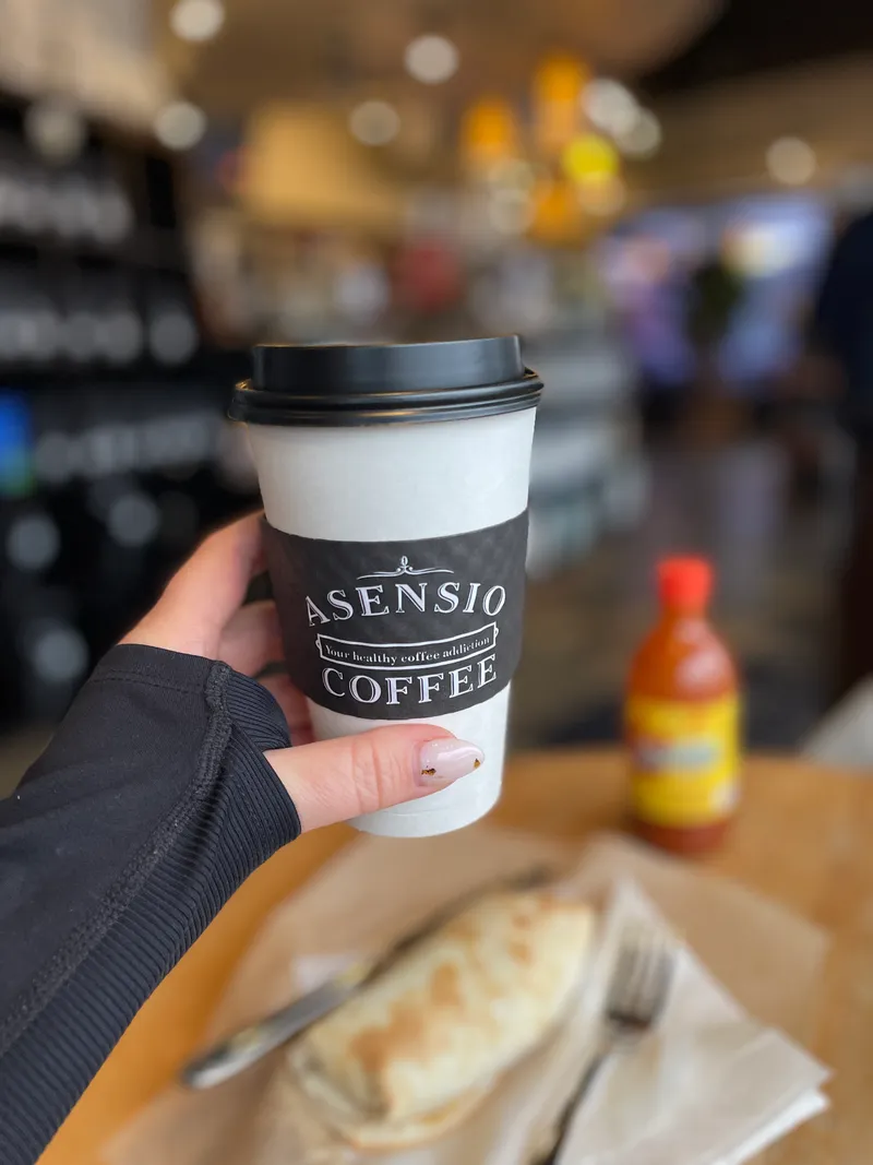Asensio Coffee branded cup with organic espresso drink, warm natural lighting